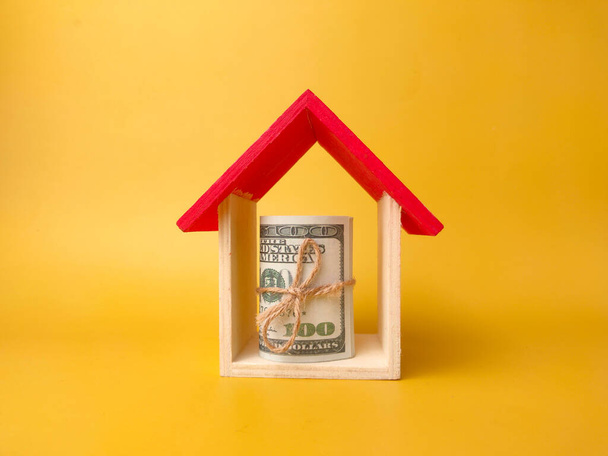 Toy house and banknotes isolated on yellow background. - Valokuva, kuva