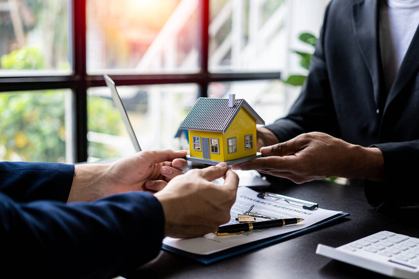 Agenci nieruchomości polecają stopy procentowe, omawiają warunki umowy kupna domu i proszą klientów o podpisanie dokumentów w celu zalegalizowania umowy. - Zdjęcie, obraz