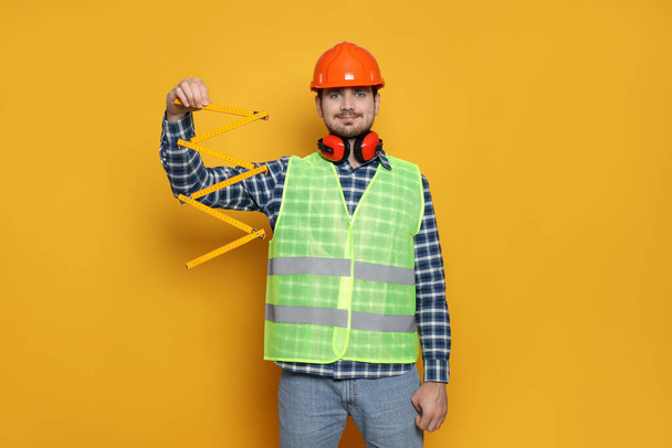 Fiatal férfi civil mérnök sárga háttér - Fotó, kép