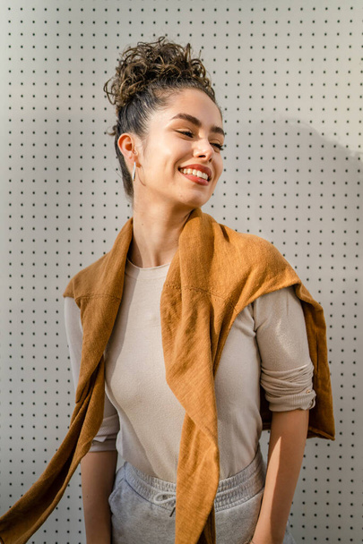 Una mujer joven adulto caucásico hembra pie al aire libre posando retrato feliz confiado en frente de la pared blanca espacio de copia - Foto, imagen