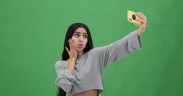Kobieta robi śmieszne miny i robi selfie za pomocą telefonu komórkowego  - Materiał filmowy, wideo