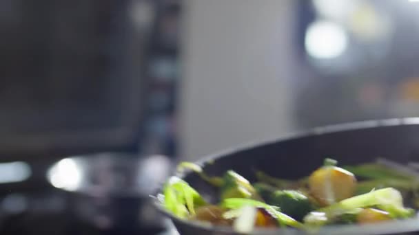 Close-up shot van het gooien van groenten op koekenpan tijdens het koken voedsel in restaurant keuken - Video