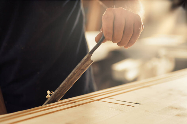 The carpenter uses a manual cutting tool to chamfer and carve the edges, smoothly removing curls and chips in a regular or irregular manner as he desires. Only a skilled artisan can achieve unique or  - Foto, Imagem