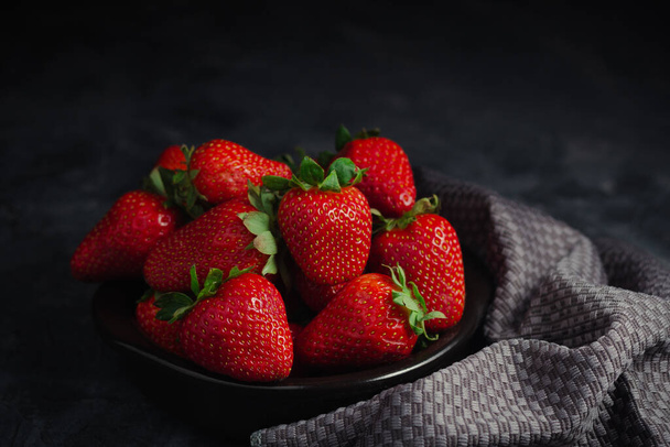 Strawbarry with gray napkin on black background. Sweet colors for social media - 写真・画像
