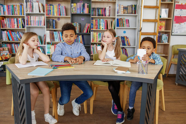 Klassenkameraden lernen im Klassenzimmer. Zurück zur Schule. Multiethnische Schüler lernen und schreiben am Tisch in der Bibliothek oder im Klassenzimmer. - Foto, Bild