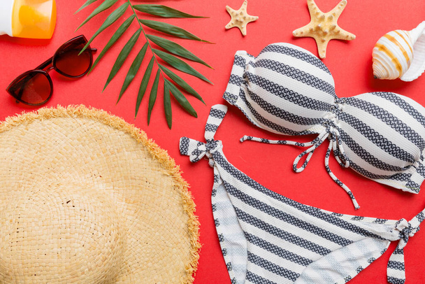 Woman swimwear and beach accessories flat lay top view on colored background Summer travel concept. bikini swimsuit, straw hat and seasheels. Copy space Top view. - Foto, Imagem