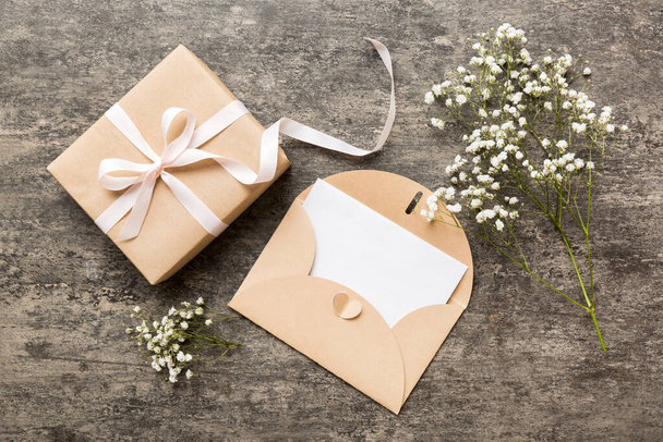 Wedding mockup with white paper list and flowers gypsophila on colored table top view flat lay. Blank greeting cards and envelopes. Beautiful floral pattern. Flat lay style. - Foto, Imagen