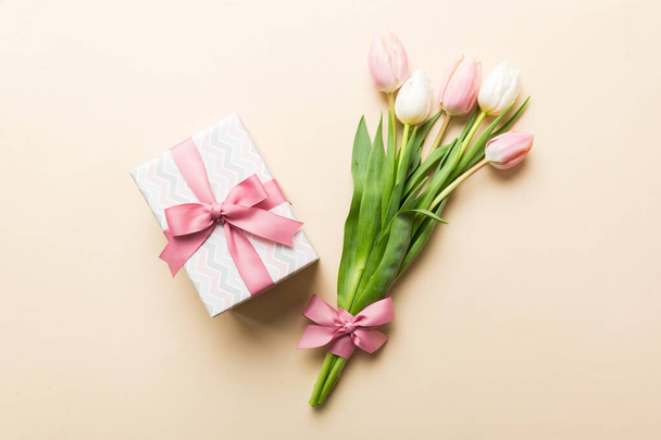 Pink tulips flowers and gift or present box on colored table background. Mothers Day, Birthday, Womens Day, celebration concept. Space for text top view. - Φωτογραφία, εικόνα