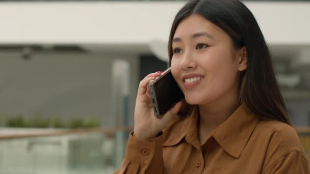 Счастливая азиатка девушка говорить мобильный телефон в офисе китайский японский бизнесмен говорить мобильный телефон разговор делового звонка удаленного общения говорить с радостной улыбкой леди говорить смех - Кадры, видео