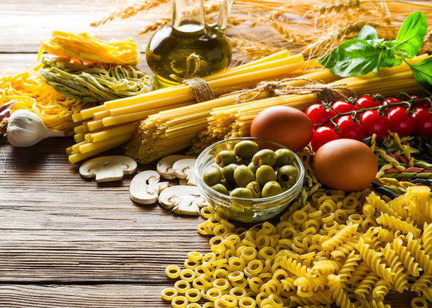 Çiğ makarna ve spagetti, kiraz domatesleri, otlar ve baharatlar, yukarıdan çekilen hafif bir masada. - Fotoğraf, Görsel