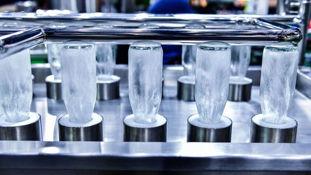 Reiniging flessen glazen flessen voor drank product in proces door warm water in automatische machine bij de productie - Foto, afbeelding