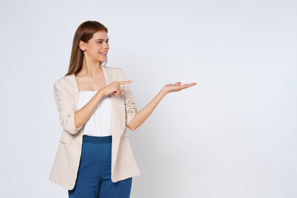 Šťastná mladá žena prezentuje nebo ukazuje otevřenou dlaň s kopírovacím prostorem pro produkt izolované na bílém pozadí. - Fotografie, Obrázek