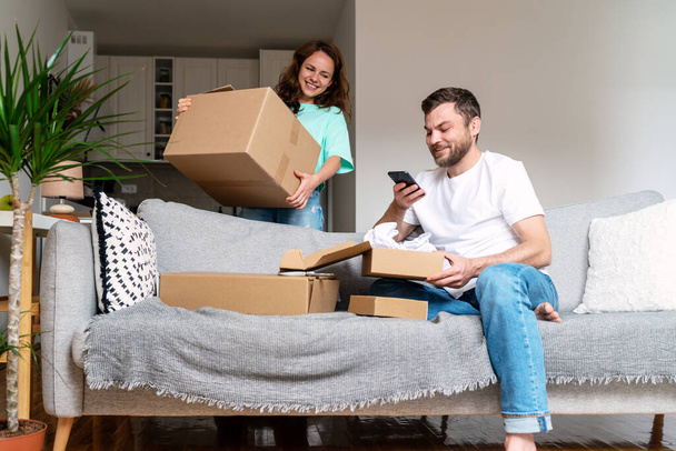 Junges Paar packt Internet-Einkauf aus, Home-Shopping-Konzept.  - Foto, Bild