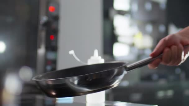 Powolny ruch zbliżenie strzał z ręki kucharza rzucanie warzyw na patelni podczas smażenia w kuchni restauracji - Materiał filmowy, wideo