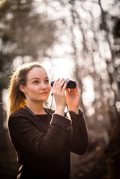 Young woman with binoculars outdoors on fall day. Enjoying the outdoors. - Foto, afbeelding