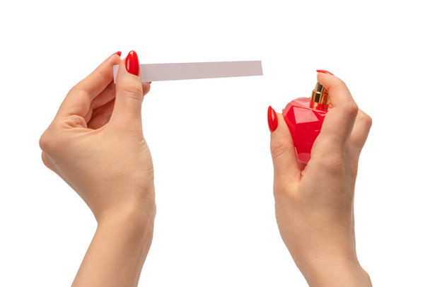 Mano de mujer con uñas rojas con tiras de prueba para el perfume, aislada sobre un fondo blanco. Bloqueadores de perfume. - Foto, Imagen