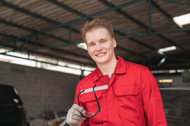 Портрет молодого автомеханика в ремонтном гараже, техник, работающий в авторемонтной мастерской, концепция ремонта и обслуживания автомобилей - Фото, изображение