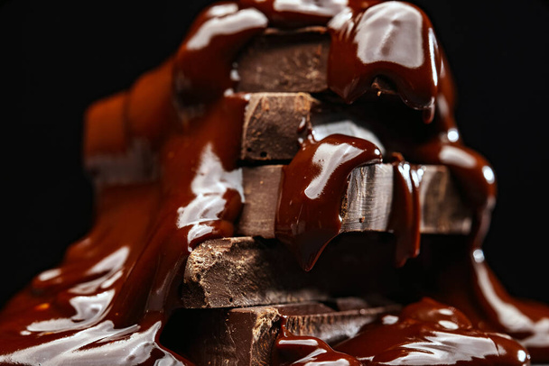 El chocolate derretido fluye sobre las barras de chocolate. - Foto, imagen
