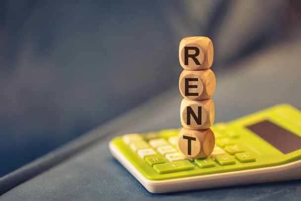 Word RENT written on wooden cubes. A calculator in the composition. Close-up - Photo, Image