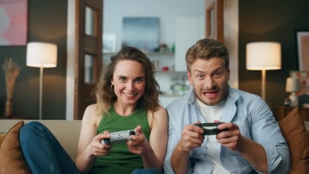 Nadšení přátelé si doma užívají videohry. Nadšení hráči drží gamepady konkurenční pov videa. Bezstarostný pár sedící pohovka tráví zábavný večer. Bavte se, koníčku volný čas koncept - Záběry, video