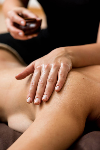 detail ženských rukou s černým masážním terapeutem na zádech - Fotografie, Obrázek