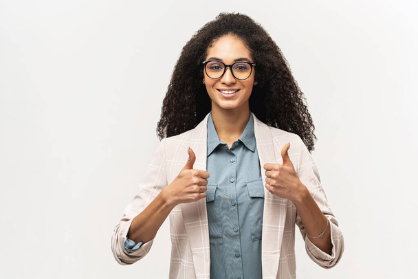 Young beautiful African American woman with curly hair in formal buisness wear and eyeglasses showing thumbs up gesture isolated on white, approving agreeing gesture - Foto, Imagem