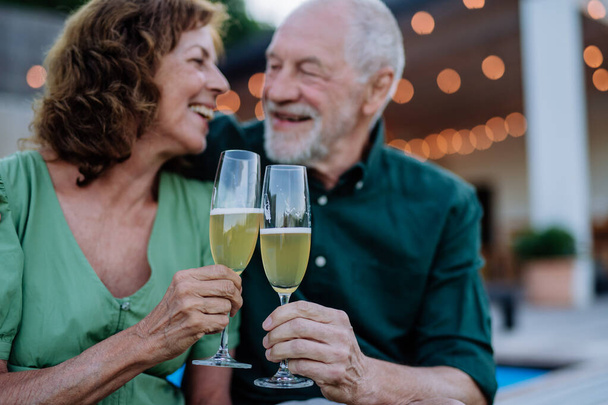 A man with his wife celebrating birthday and toasting with wine near backyard pool. - Foto, imagen