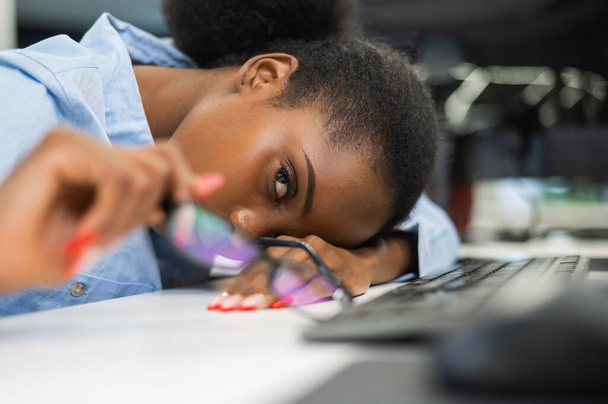 African young woman sleeping at work desk - Фото, изображение
