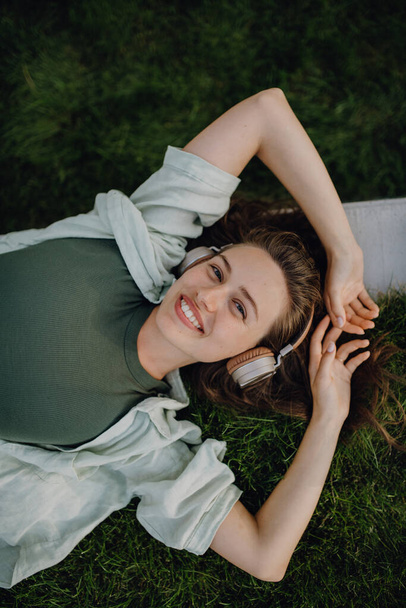 Young woman resting in a city, enjoying the music trough headphones. - Photo, Image
