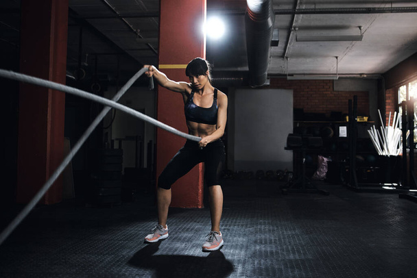 Concéntrate en tus objetivos. una joven haciendo entrenamiento de cuerda pesada en el gimnasio - Foto, Imagen