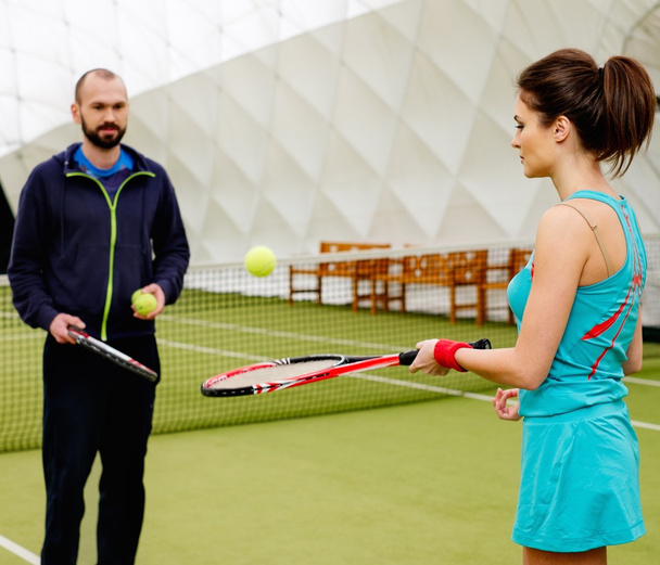 Woman and her coach practicing on a tennis court - Photo, Image