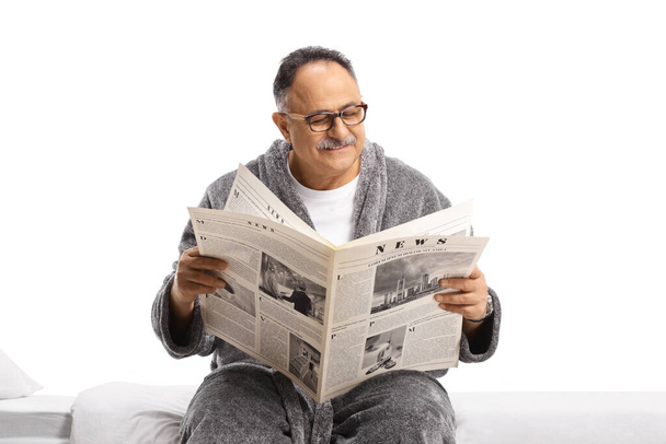 Mature man in a robe relaxing with a newspaper isolated on white background - Photo, Image