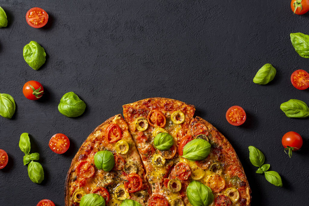 Pizza Margherita z pomidorem bazyliowym i mozzarellą, widok z góry na czarne tło zbliżenie. - Zdjęcie, obraz