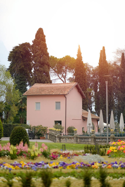 Gardajärvi, Italia - 04 15 2023: Vaaleanpunainen talo Italian tyyliin sijaitsee puutarhassa ja ympäröi upea luonto - Valokuva, kuva