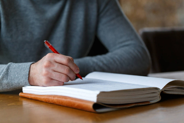 Business man in casual clothes writing with red pen in a journal  - Фото, изображение