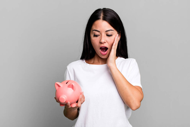 hispanic pretty woman feeling happy, excited and surprised with a piggy bank - Fotoğraf, Görsel