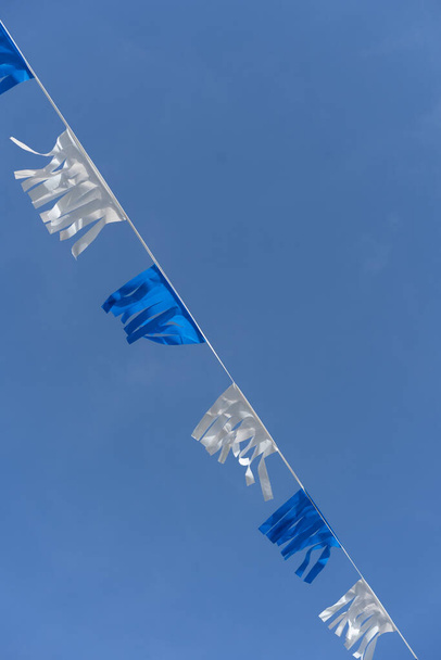 Israeli blue and white flag bunting fluttering against a backdrop of blue sky with white clouds on Independence Day of Israel. Perfect for projects related to Israeli culture and celebrations. - Photo, Image