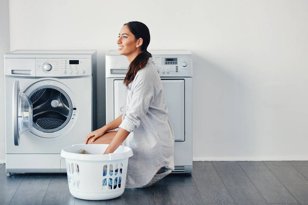 Elegí el día perfecto para lavar. una joven atractiva lavando su ropa en casa - Foto, imagen