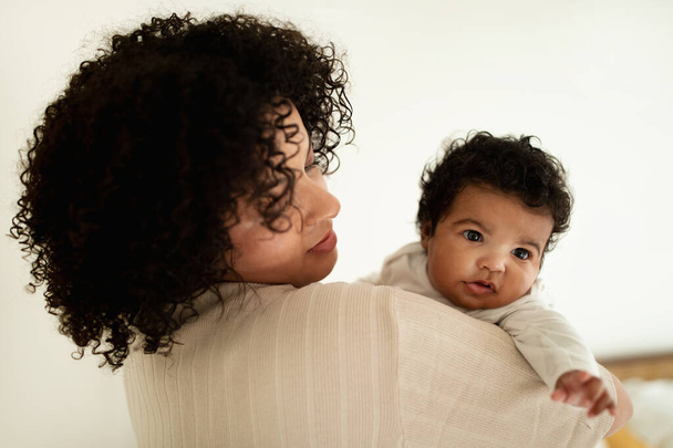 Mujer afroamericana milenaria jugando con un niño pequeño, disfrutar de la maternidad, relajarse y divertirse juntos, en el dormitorio, de cerca. Cuidado del bebé, amor, madre e hijo recién nacido en casa - Foto, Imagen