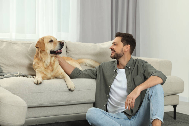 Happy man with his cute Labrador Retriever at home - Fotoğraf, Görsel