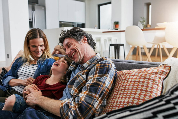 Ailemiz sevgi ve kahkaha ile dolu. Üç kişilik sevgi dolu bir aile evdeki kanepede dinleniyor. - Fotoğraf, Görsel