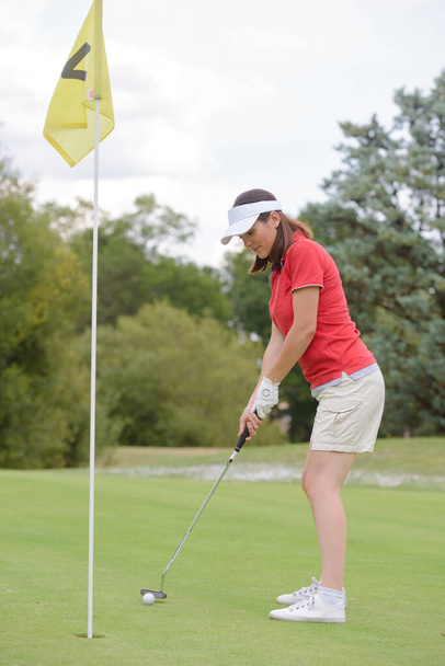 woman golfer aiming to putt ball into hole - Foto, immagini
