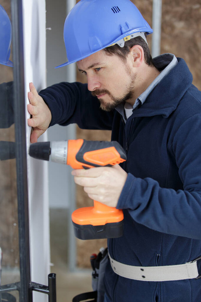 man drill a plastic window - Foto, afbeelding