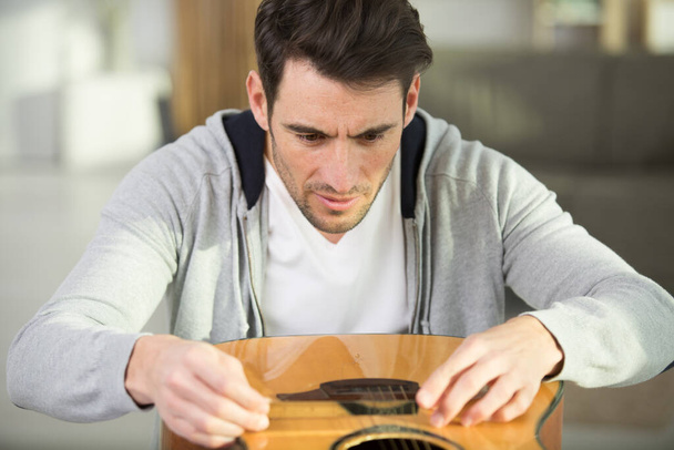 mies korjaa hänen kitara kielet - Valokuva, kuva