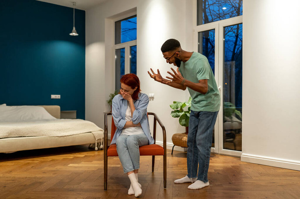 Νευρικός θυμωμένος σύζυγος Αφροαμερικάνος άντρας που ουρλιάζει προσπαθεί να εξηγήσει να αποδείξει κάτι στην υστερική αγχωμένη Ευρωπαία γυναίκα σύζυγο. Διαφορετικό οικογενειακό ζευγάρι έχει κατ 'οίκον σύγκρουση. Κατάχρηση, ψυχολογική πίεση - Φωτογραφία, εικόνα
