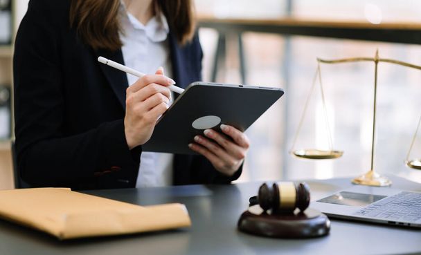 justice and law concept.female judge in a courtroom  the gavel, working with  digital tablet computer on  table - Foto, afbeelding