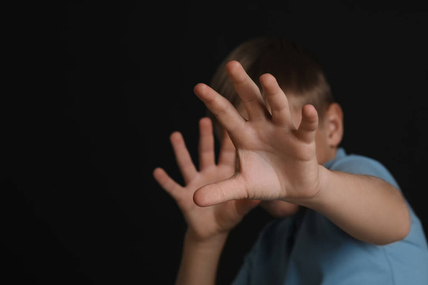Boy making stop gesture against black background, focus on hands and space for text. Children's bullying - Foto, Imagen
