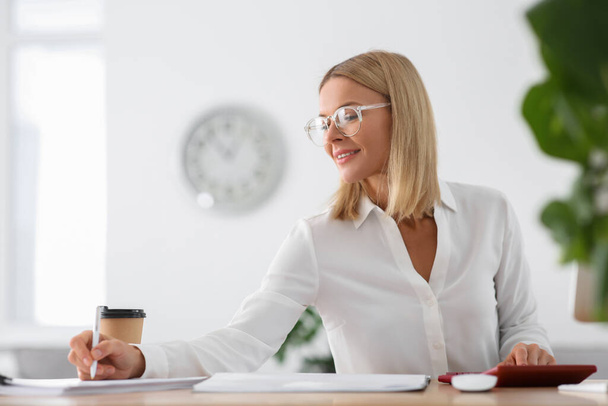 Happy woman working with documents at wooden table in office - Foto, Imagem