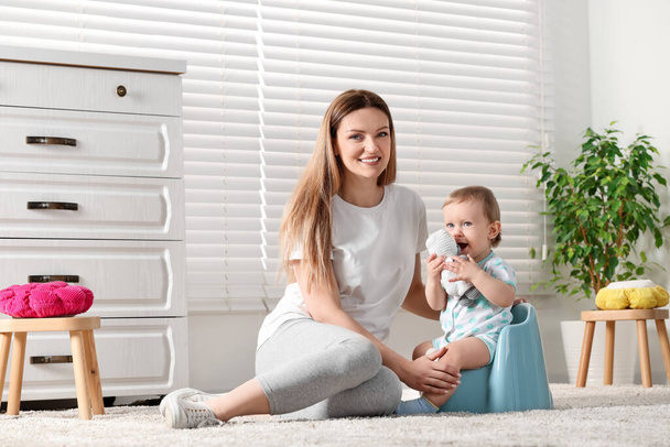 Mother training her child to sit on baby potty indoors - Foto, Bild