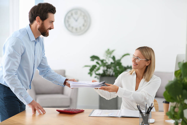 Man giving documents to colleague in office - Foto, imagen